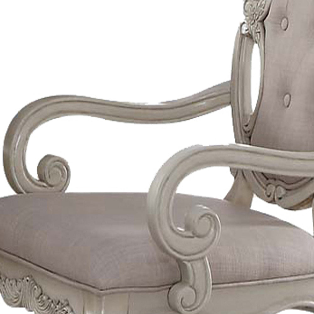Ornate carved armrest of a light grey upholstered accent chair