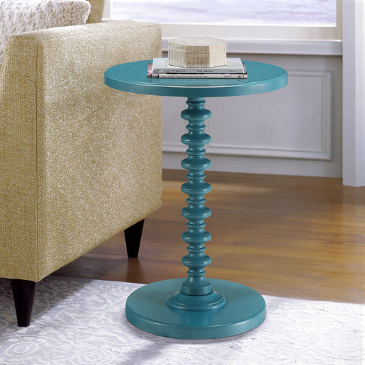 Teal round accent table with carved pedestal base and stacked books