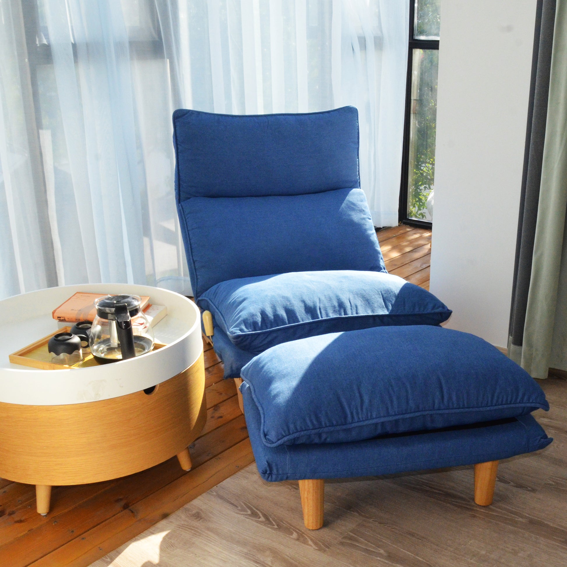 Deep blue upholstered floor chair with adjustable back and matching ottoman perfect for relaxation