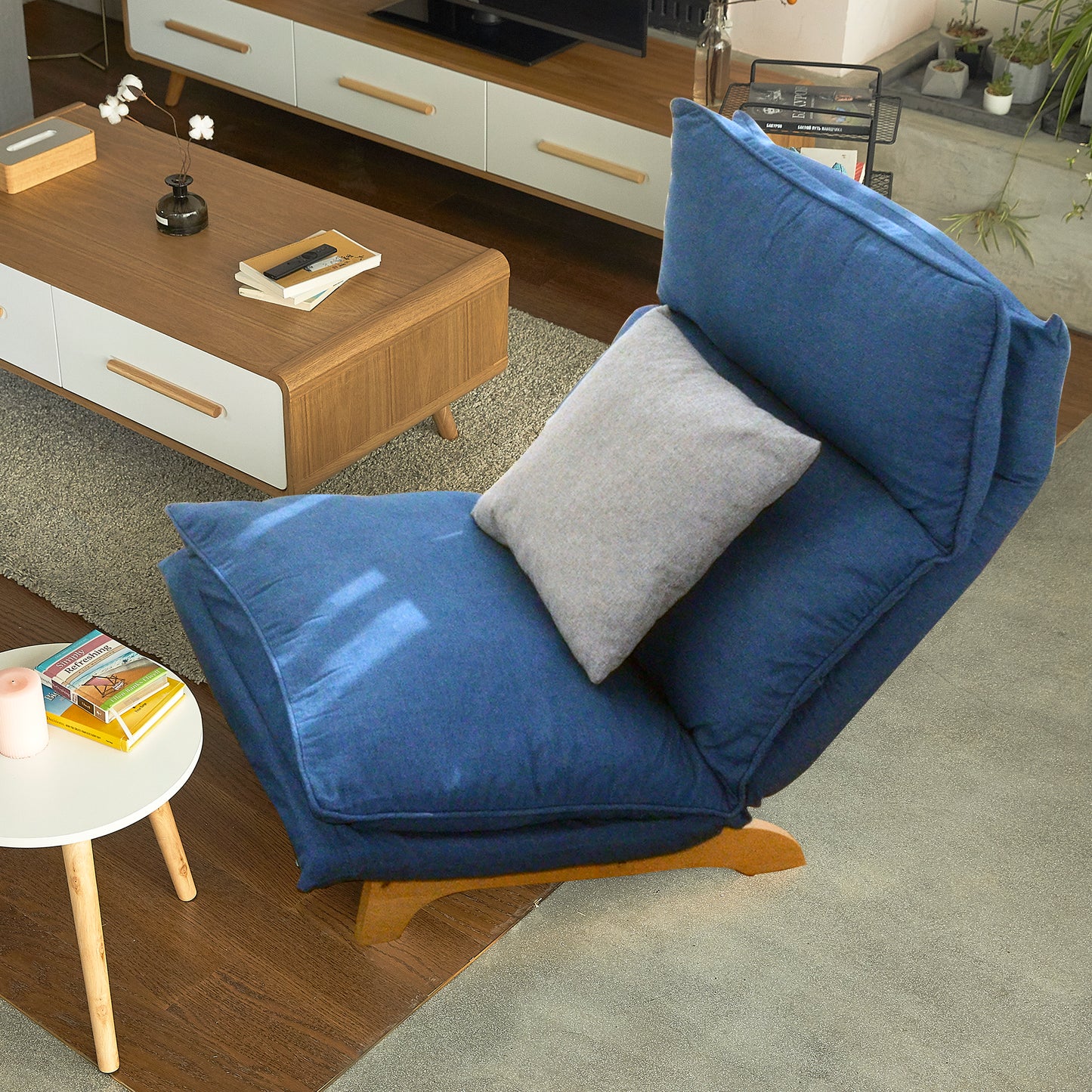 Deep blue fabric floor chair with adjustable back and light gray accent pillow