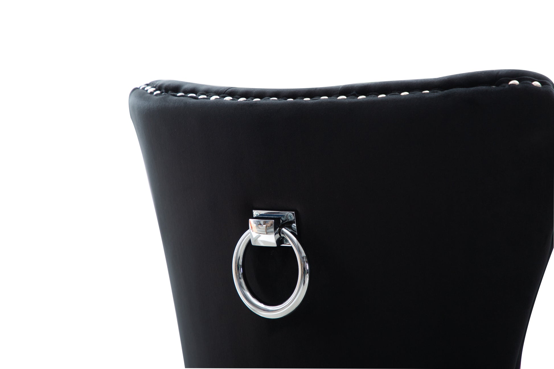 Close up of a black velvet dining chair back with silver studding and a chrome ring pull detail