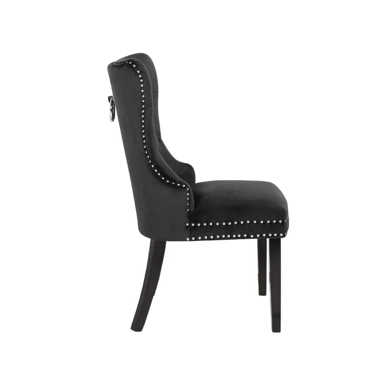 Black velvet tufted dining chair with silver nailhead trim and a decorative ring pull