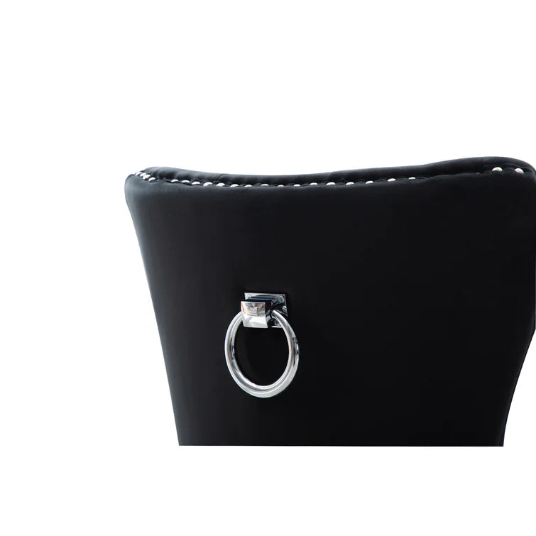 Close up of a black tufted dining chair with a silver ring accent on white background