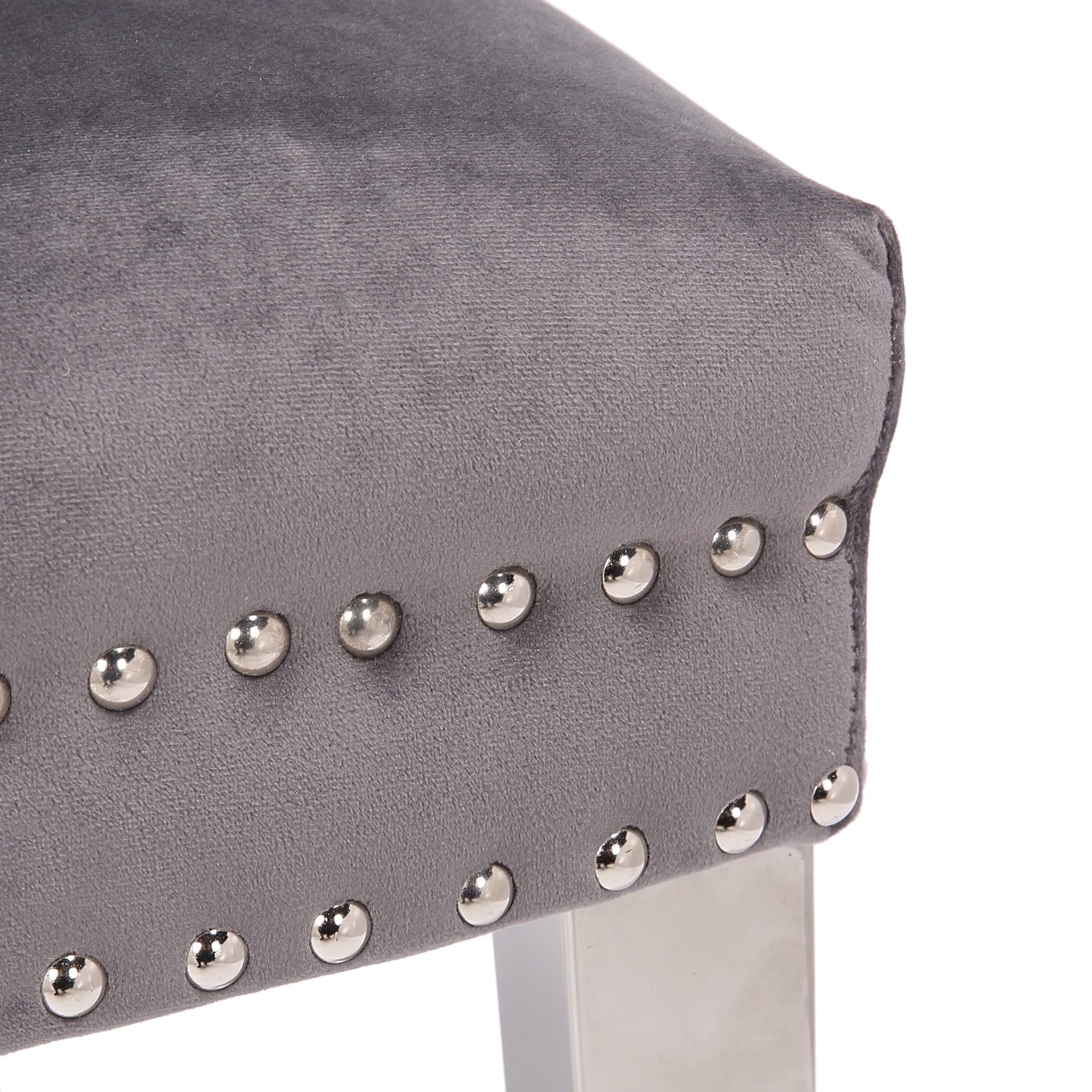 Closeup of a grey velvet dining chair with silver nailhead trim detailing