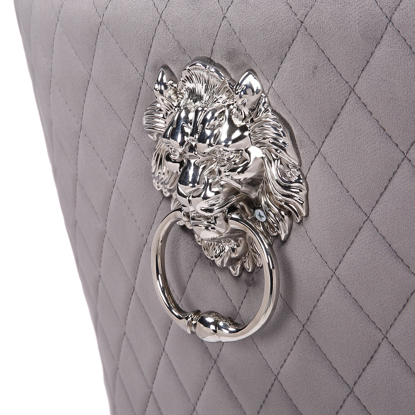Closeup of a quilted grey velvet chair back with a silver lion head knocker detail
