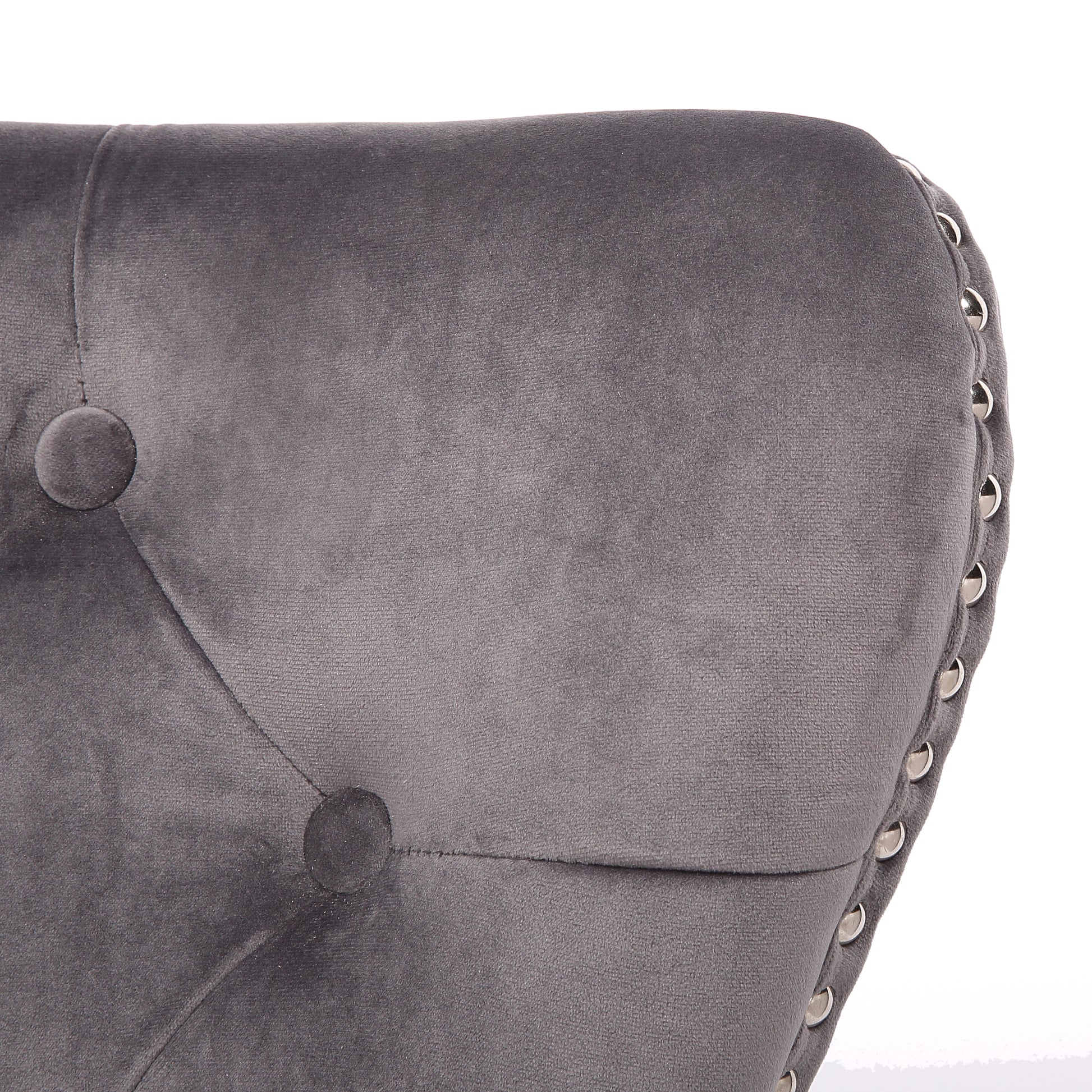 Closeup of a grey velvet tufted accent chair with silver nailhead trim