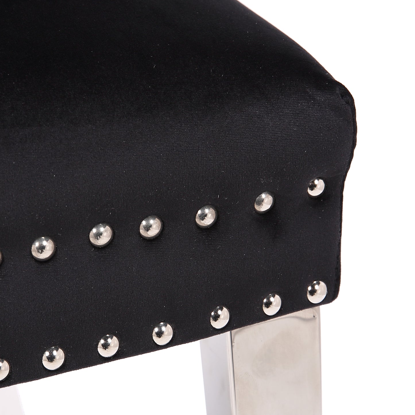 Black velvet armchair detail with silver stud trim and polished metal legs