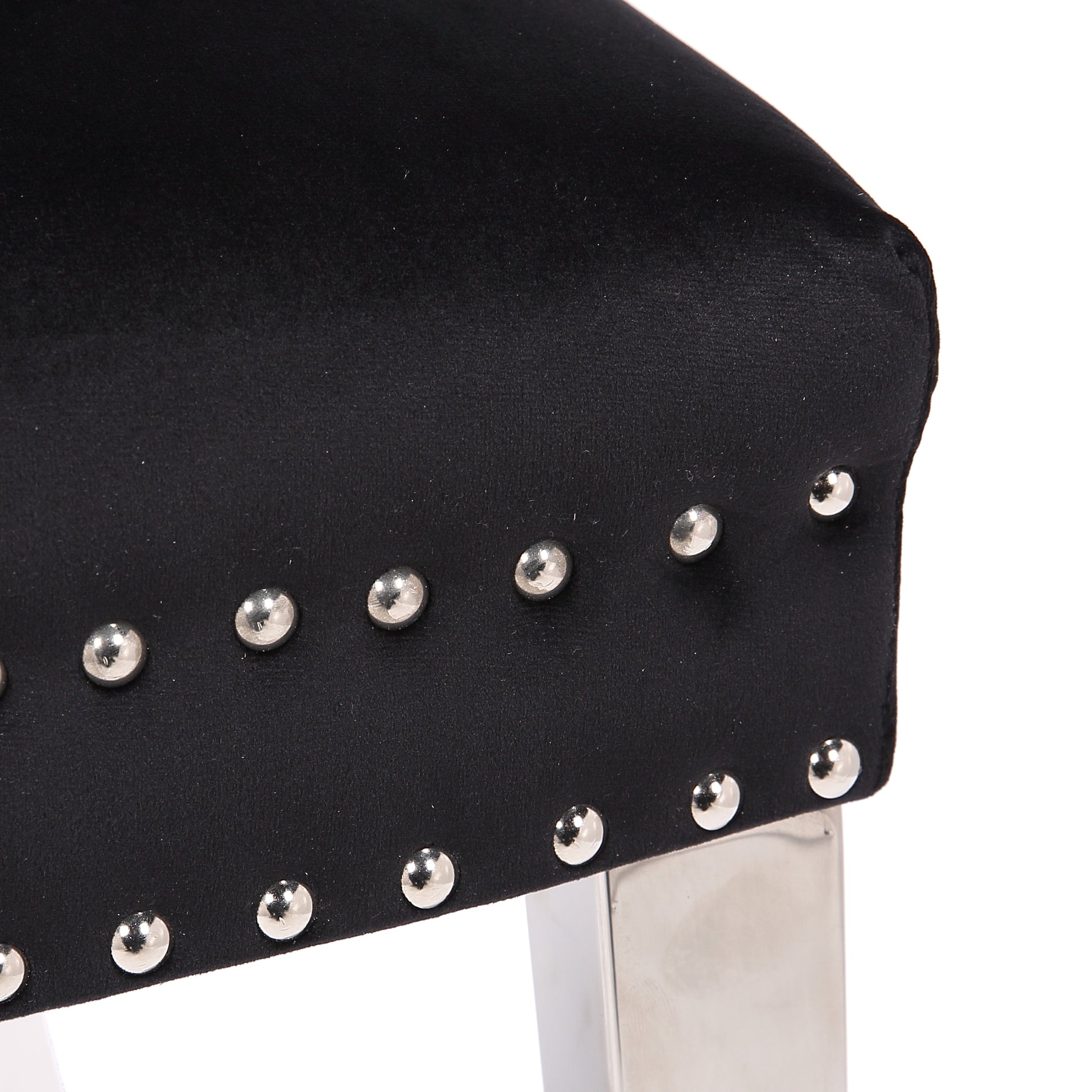 Black velvet armchair detail with silver stud trim and polished metal legs