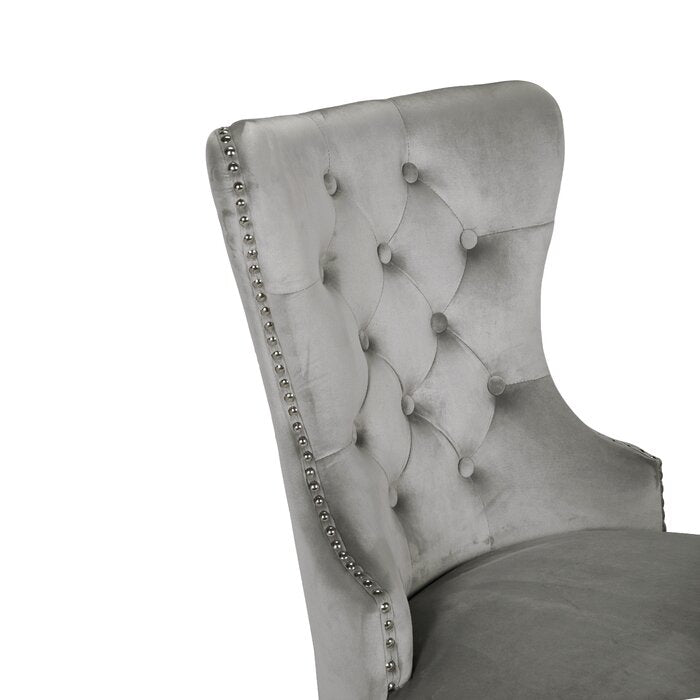 Closeup of a silver velvet tufted dining chair with nailhead trim