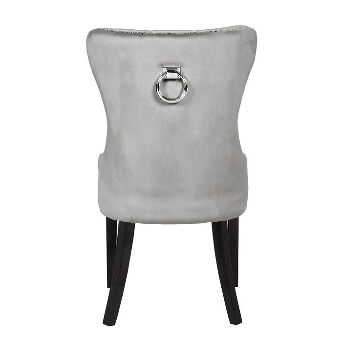 Back of a silver velvet dining chair with a chrome ring pull handle and black tapered legs
