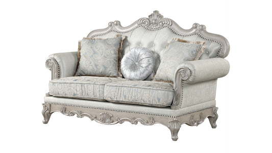 Classic tufted loveseat with ornate silver carved details and paisley accent pillows