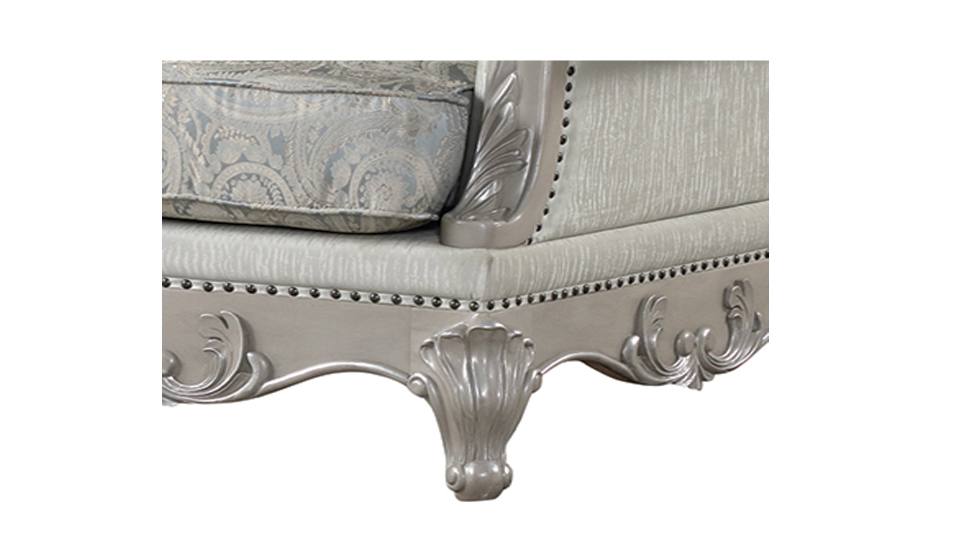 Closeup of a silver Louis XVI style armchair with ornate carving and plush cushions