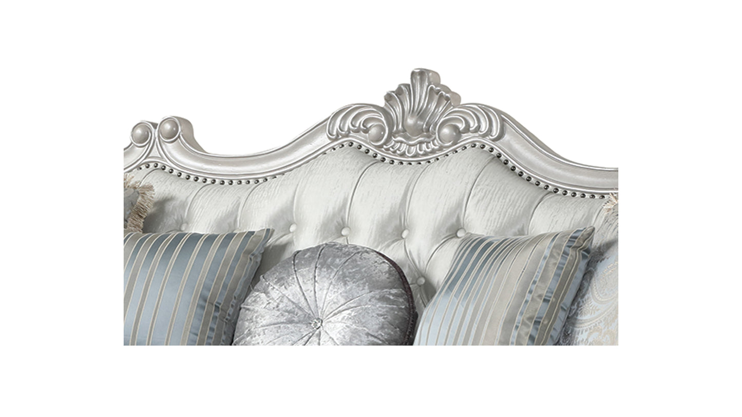 White tufted headboard with ornate silver trim and plush decorative pillows