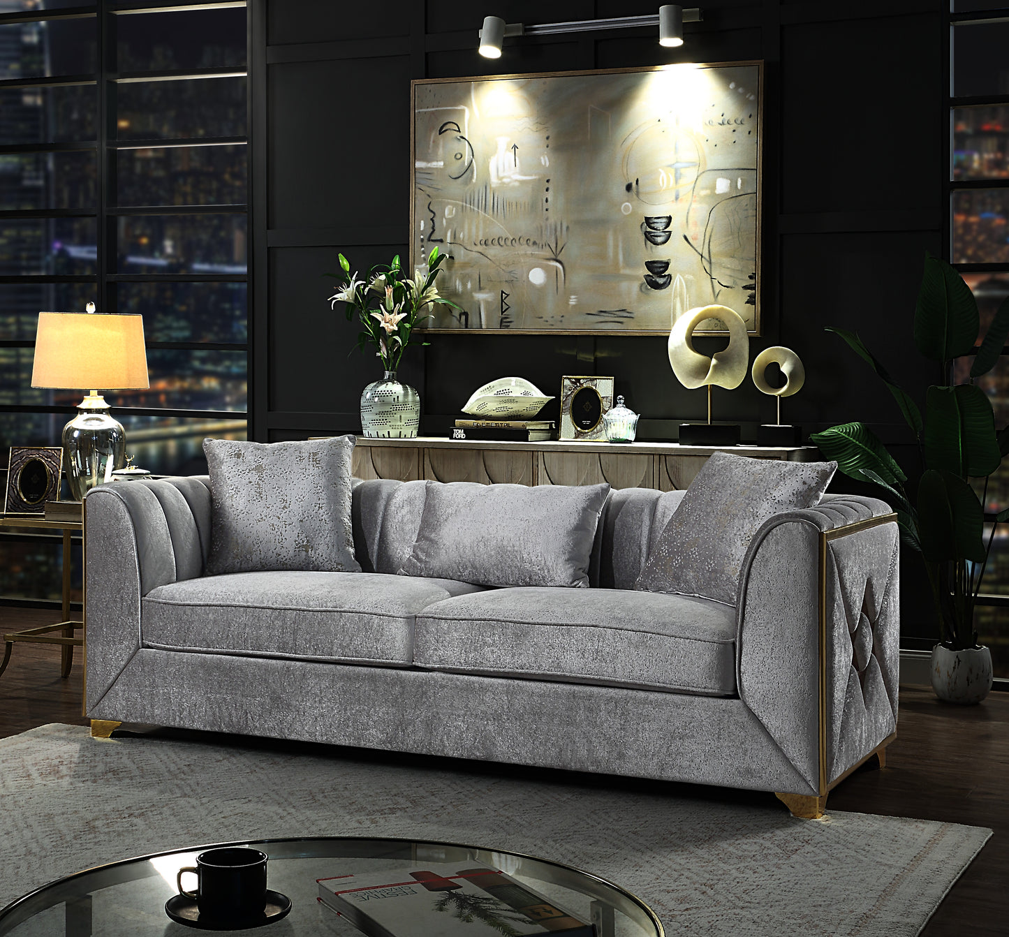 Grey velvet sofa with plush cushions and gold trim accents