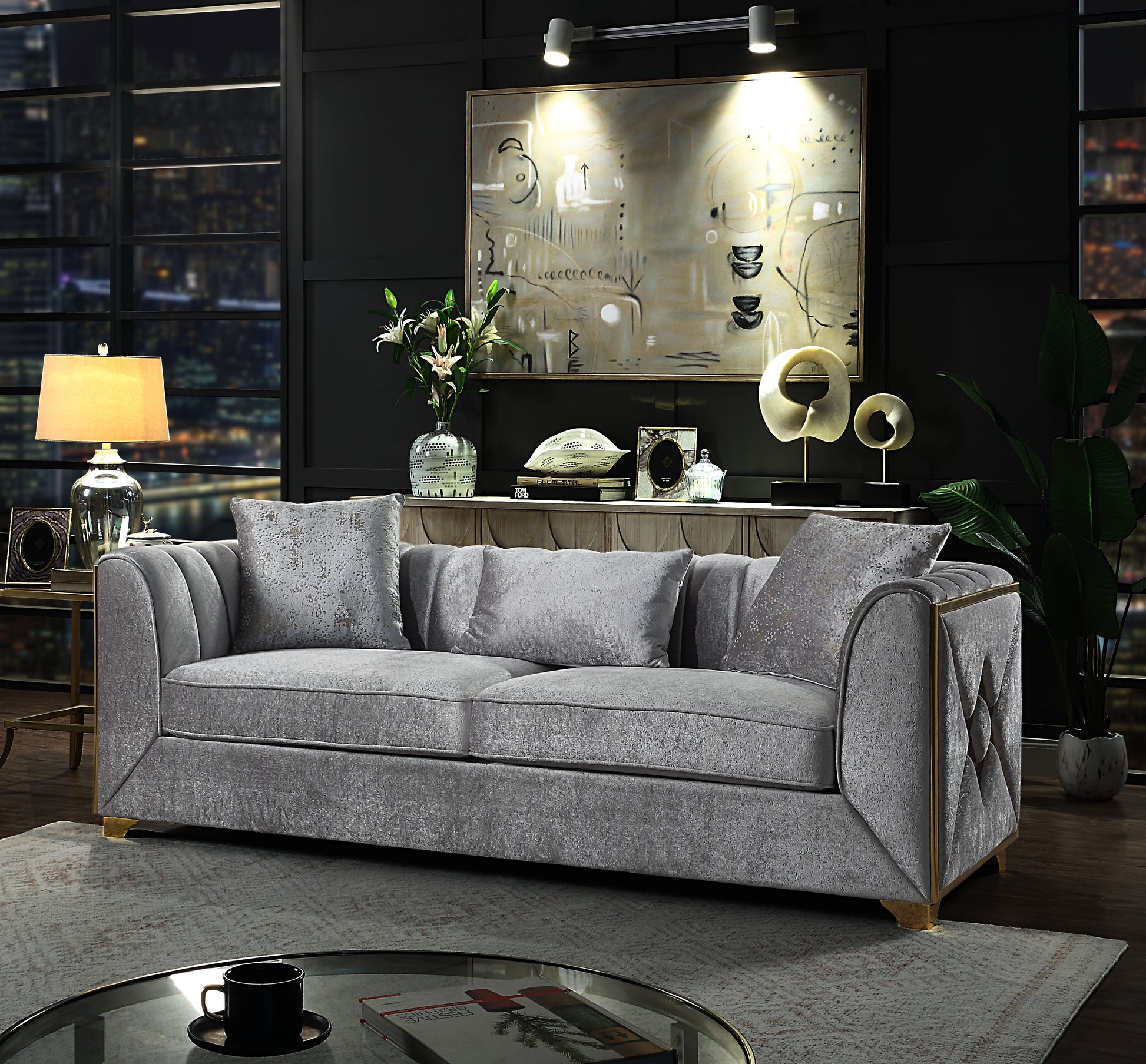 Grey velvet sofa with plush cushions and gold trim accents