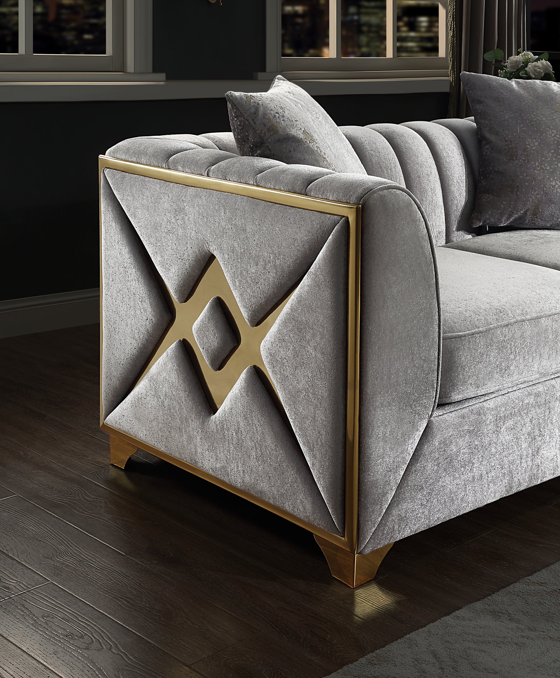 Gray velvet sofa with gold geometric trim and tufted accents