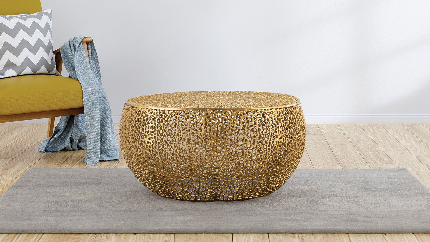 Ornate gold metal coffee table with intricate cutouts and a rounded silhouette