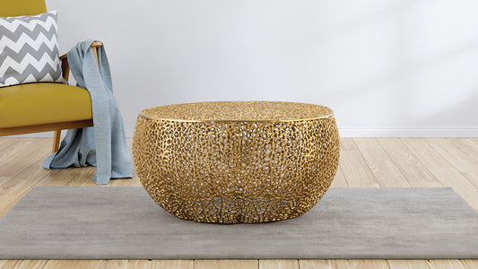 Ornate gold metal coffee table with intricate cutouts and a rounded silhouette