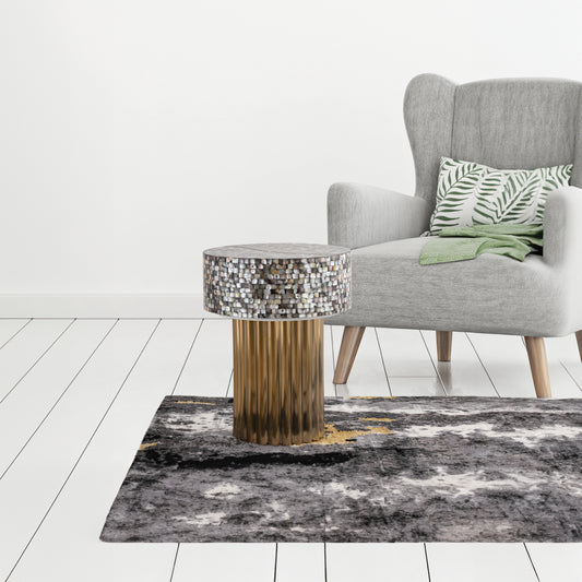 Grey armchair with palm leaf pillow and green throw next to mosaic accent table