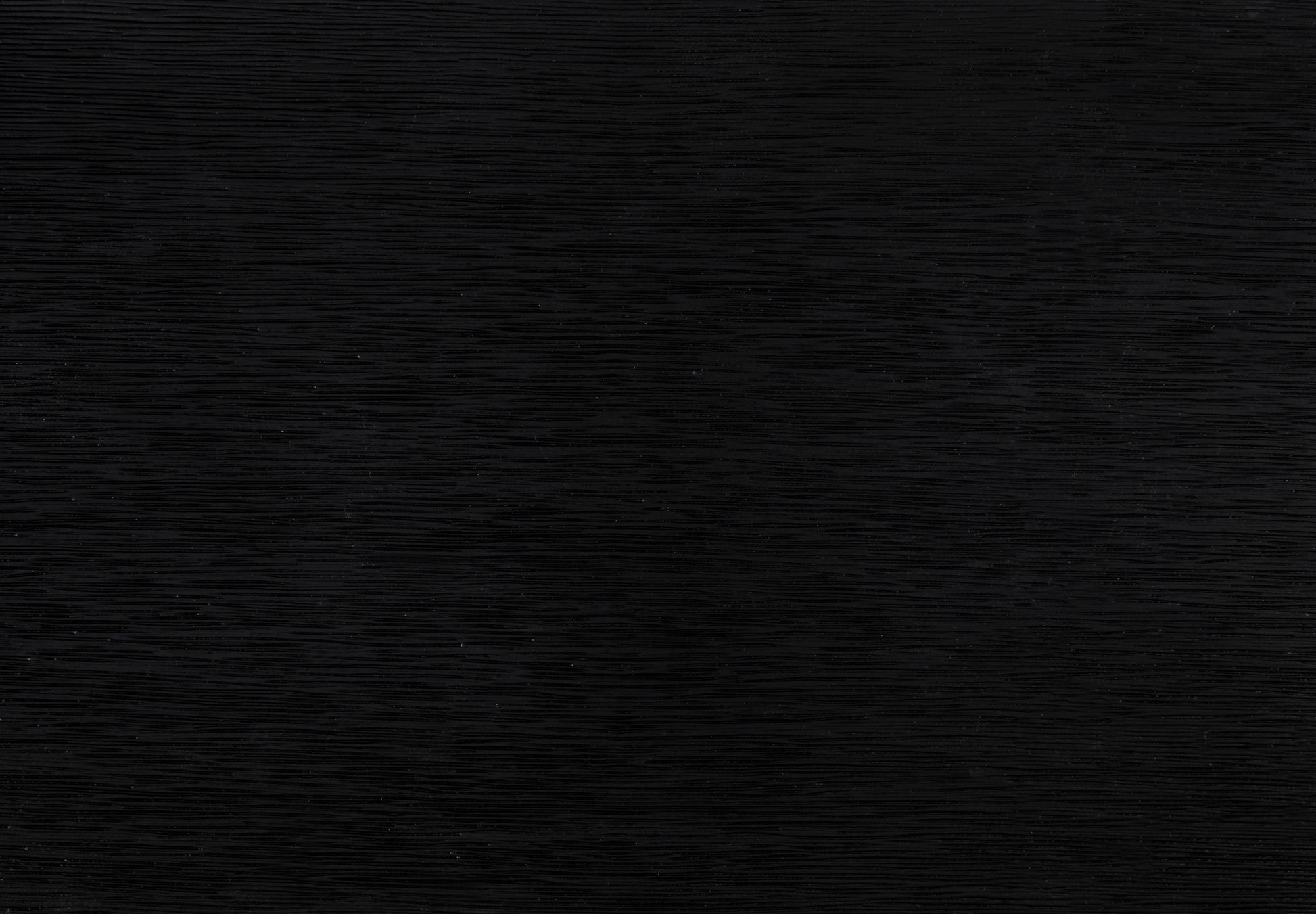 Closeup of a textured black wood veneer sample showcasing its horizontal grain pattern