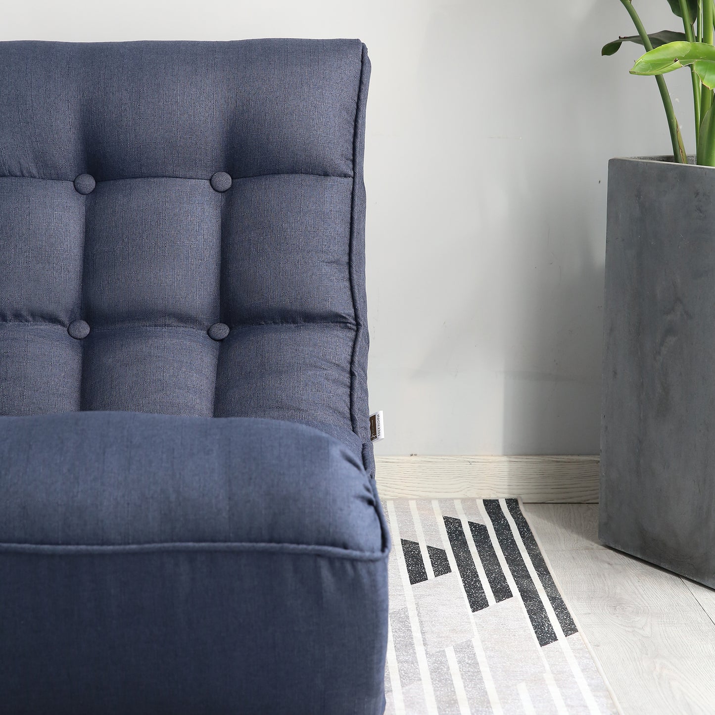 Closeup of a tufted navy blue upholstered armchair showcasing button details and linenlike fabric