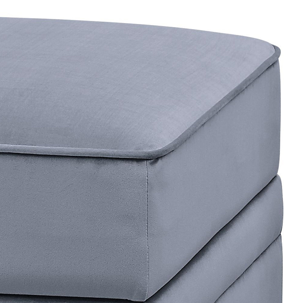 Closeup of a plush grey velvet ottoman with piped edges perfect for adding comfort