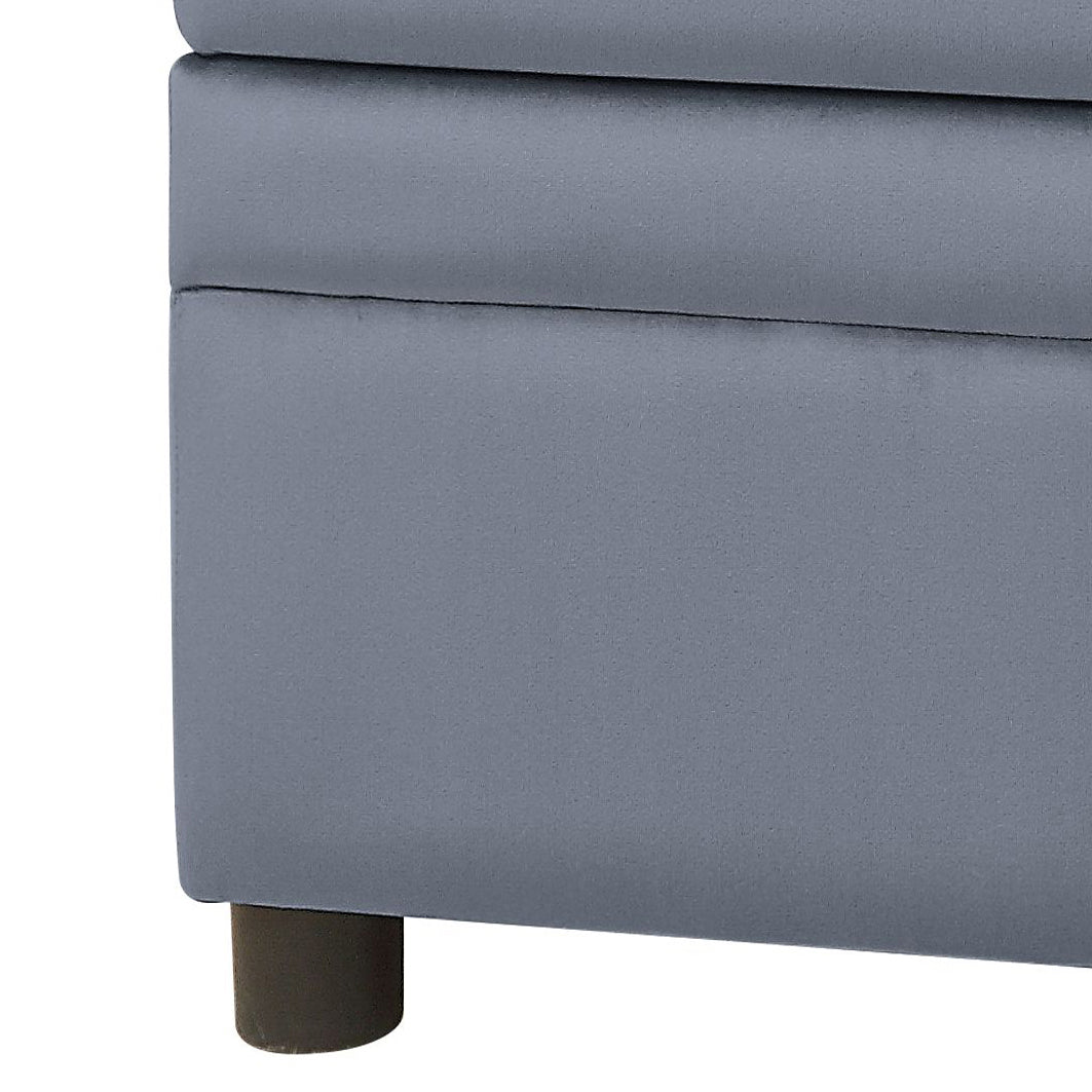 Closeup of a dark grey storage ottoman with clean lines and a single dark brown wooden leg