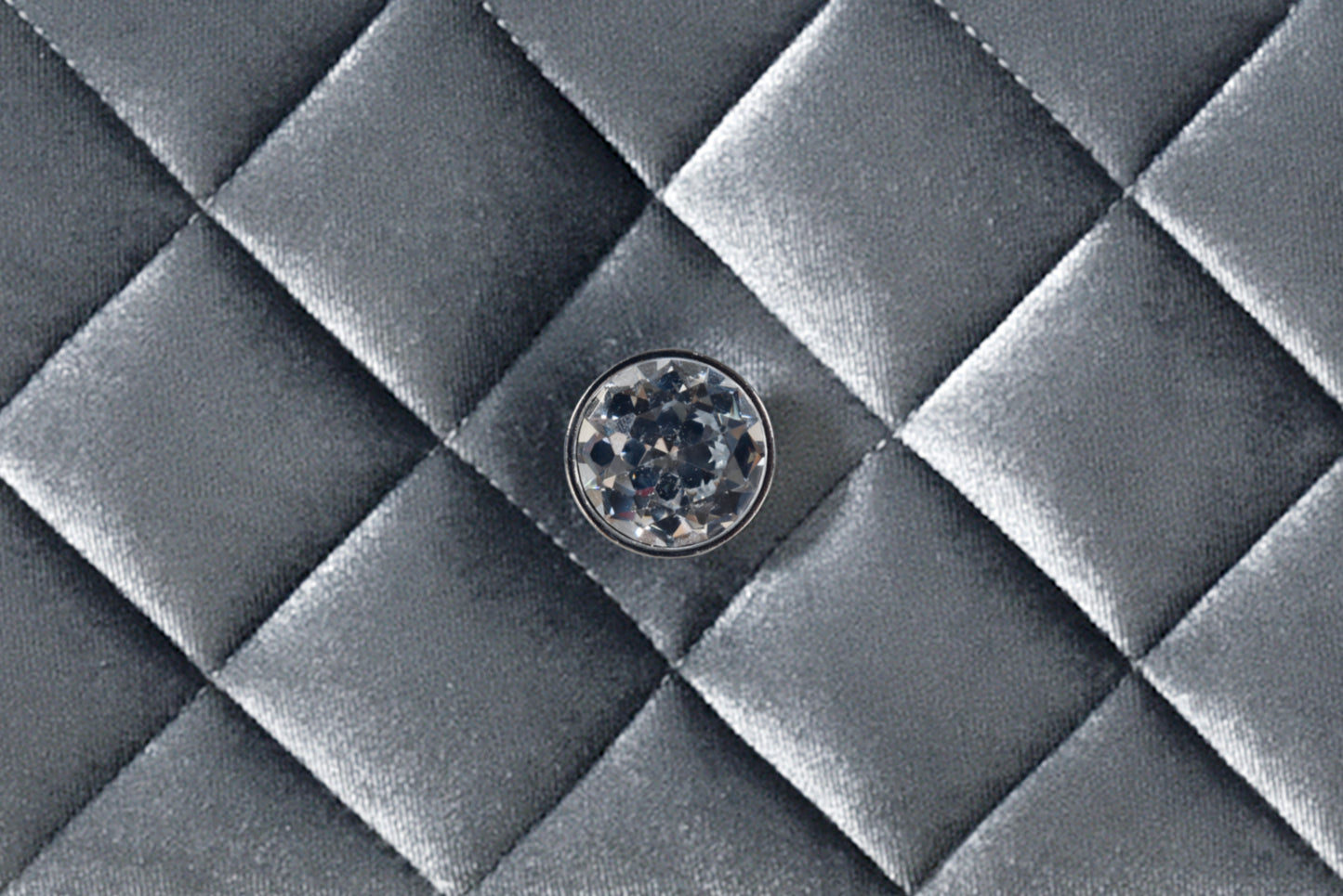 Closeup of a silver quilted fabric texture with a faceted crystal embellishment detail