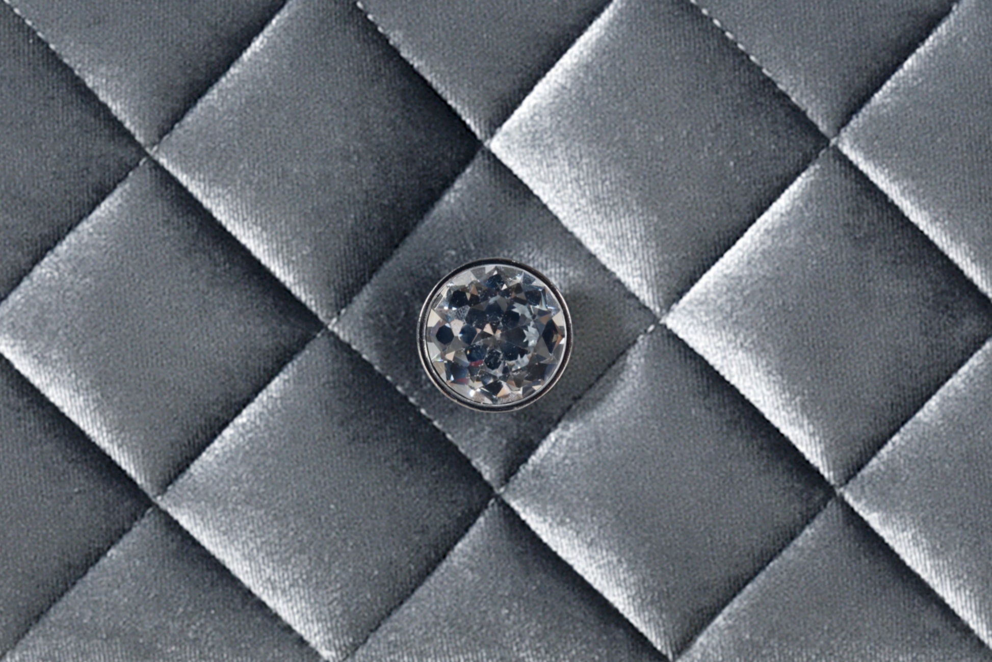 Closeup of a silver quilted fabric texture with a faceted crystal embellishment detail