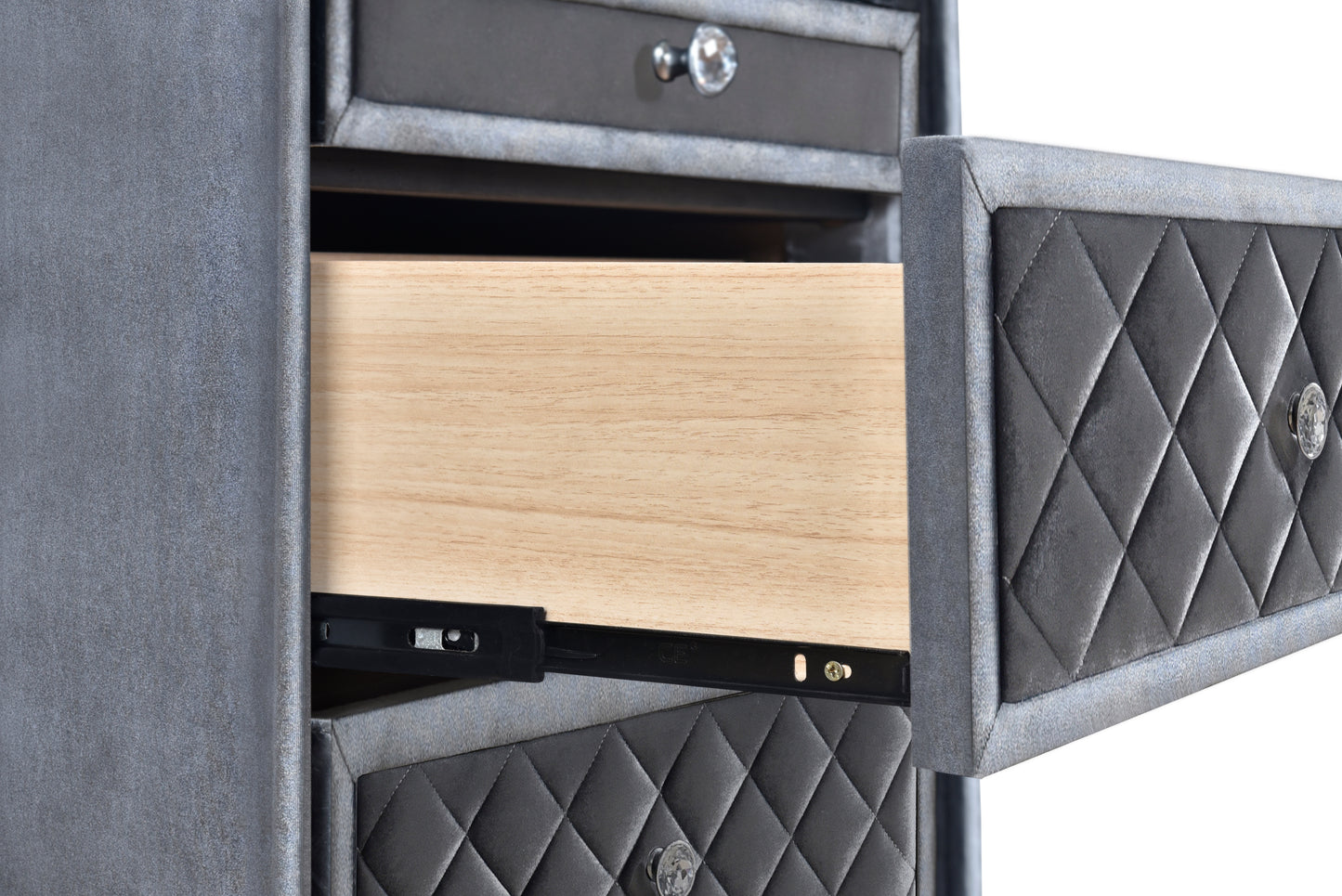 Closeup of a grey velvet upholstered nightstand with a partially opened drawer revealing a wooden interior