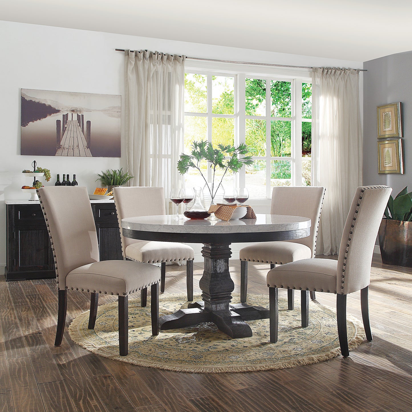Round marble top dining table with dark pedestal base and upholstered chairs