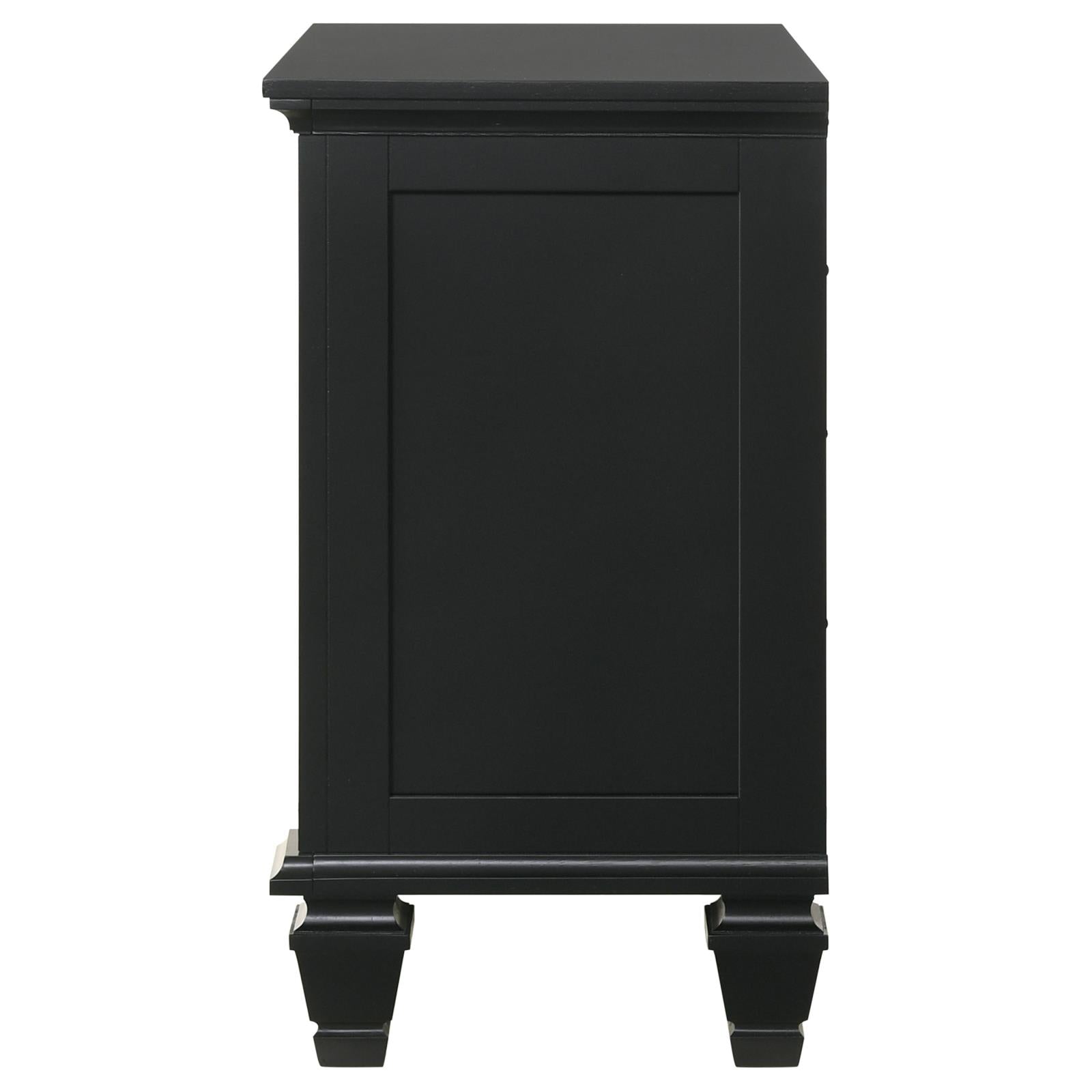 Side view of a black wooden nightstand with a paneled drawer front and decorative legs