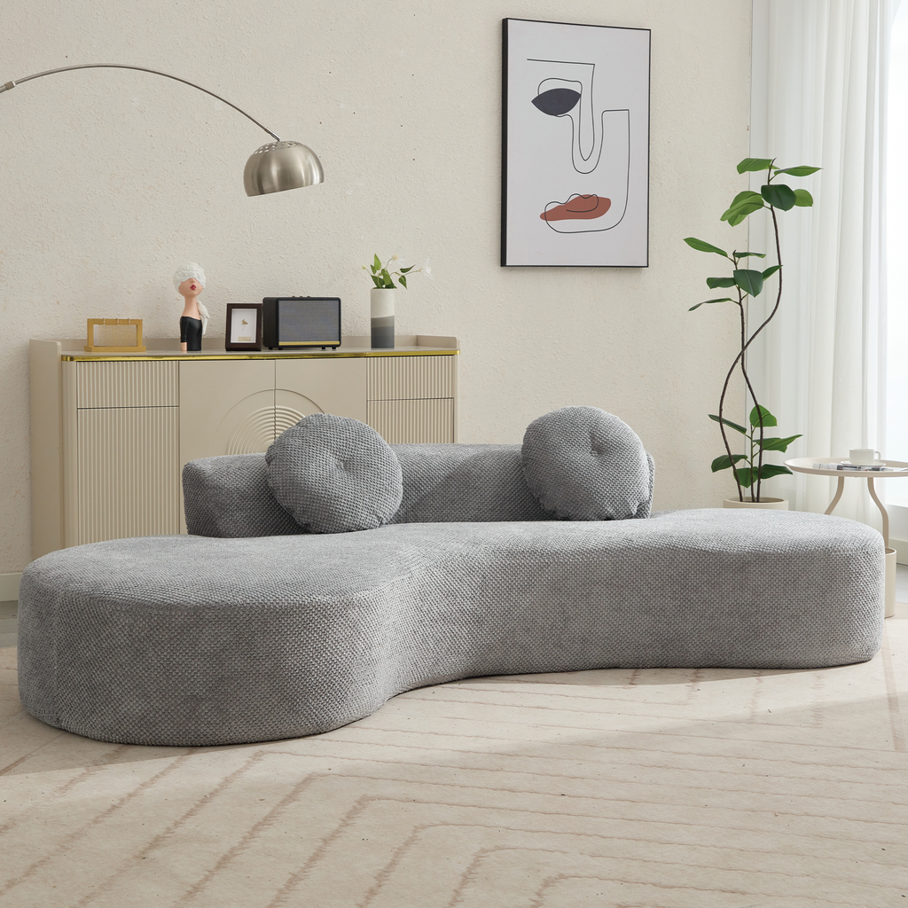 Modern curved grey sofa with textured fabric and round bolsters