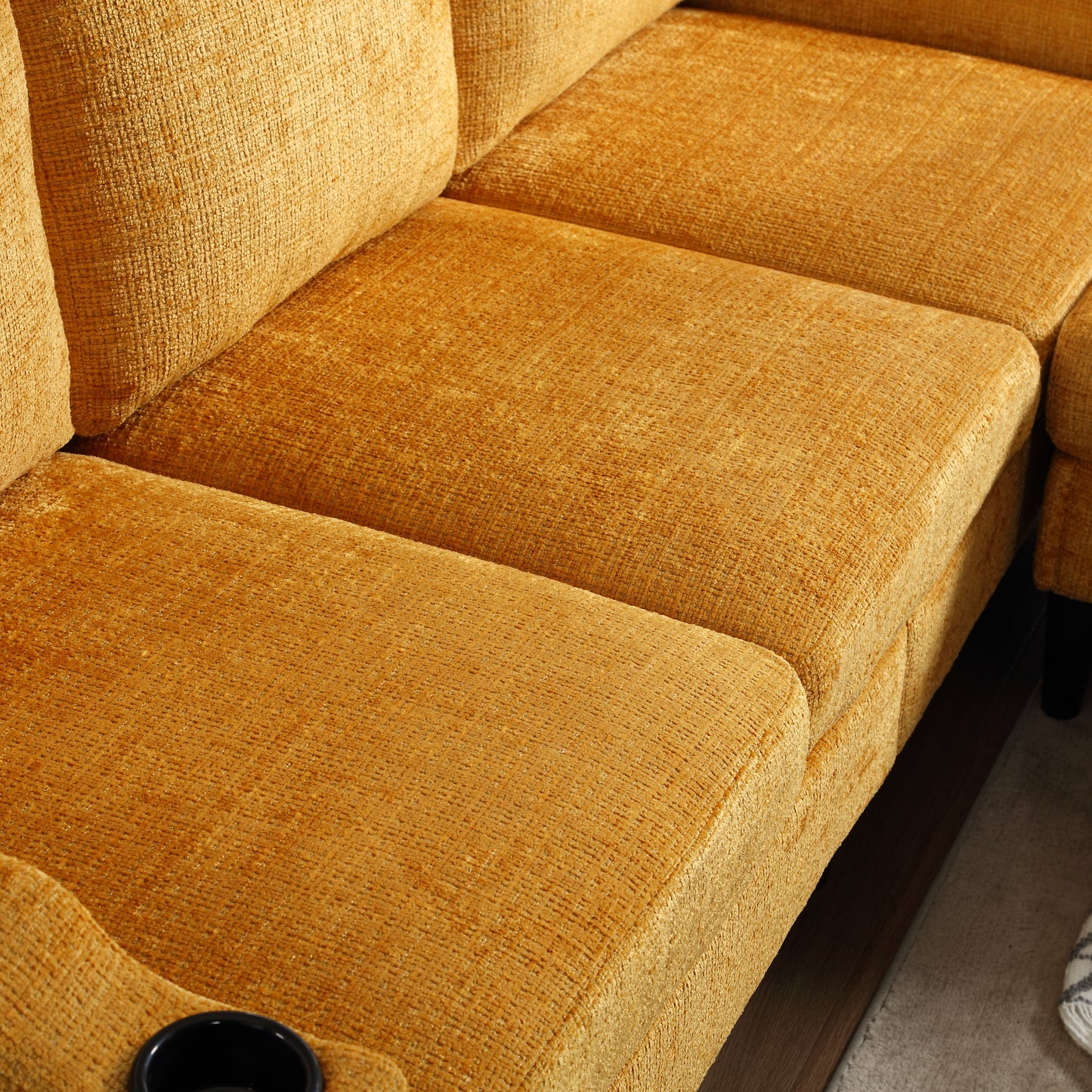 Closeup of a textured mustard yellow velvet sofa with a builtin cup holder