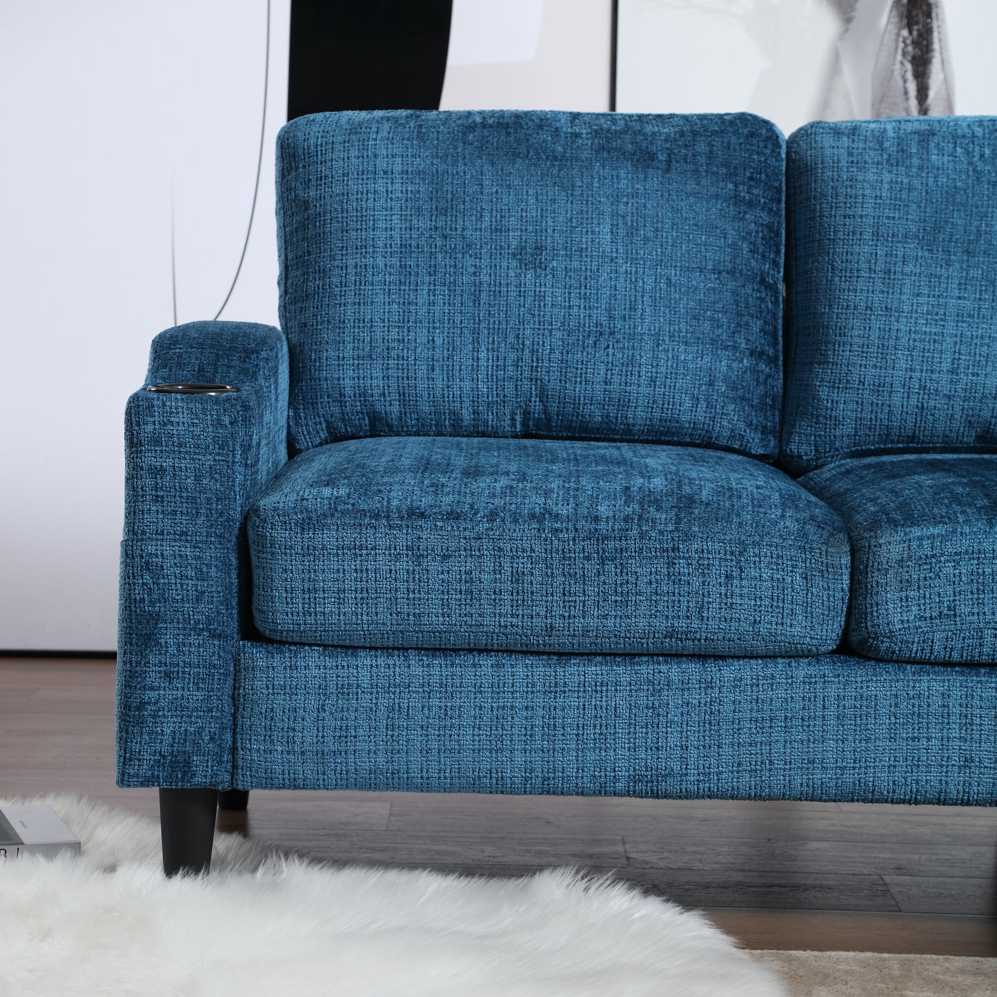 Closeup of a textured teal fabric sofa with a builtin cup holder on the armrest