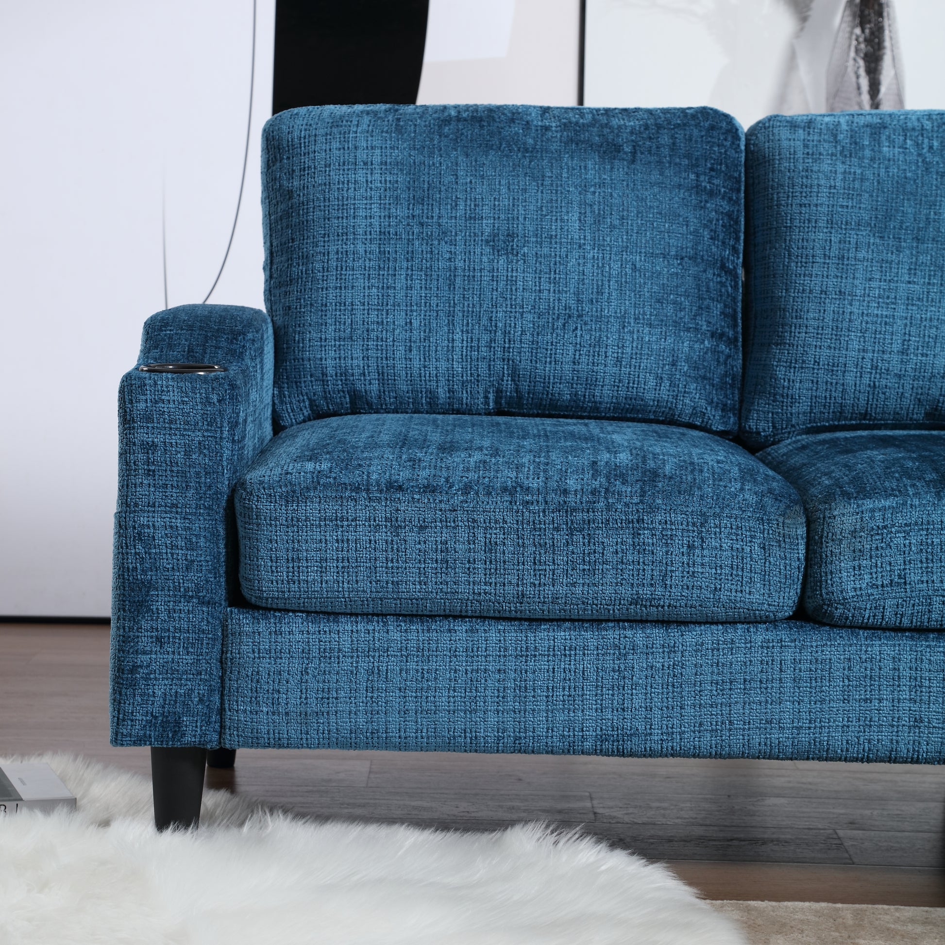 Closeup of a textured teal fabric sofa with a builtin cup holder on the armrest