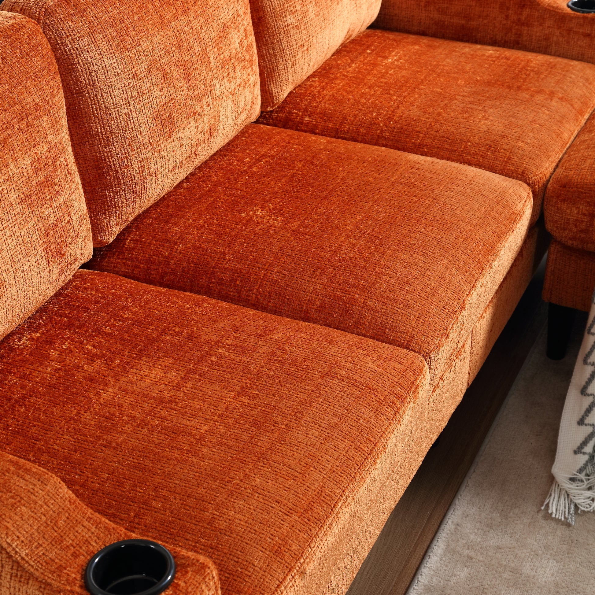 Closeup of orange velvet sofa cushions with integrated cup holder