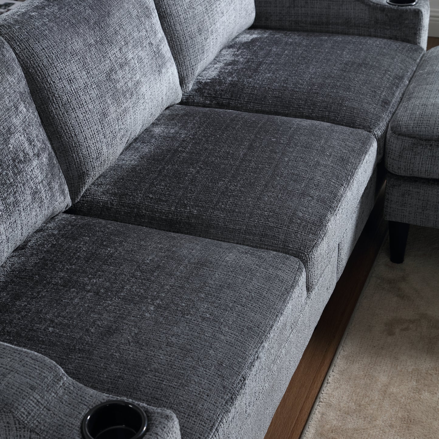 Closeup of a plush grey fabric sofa with integrated cup holders for home entertainment