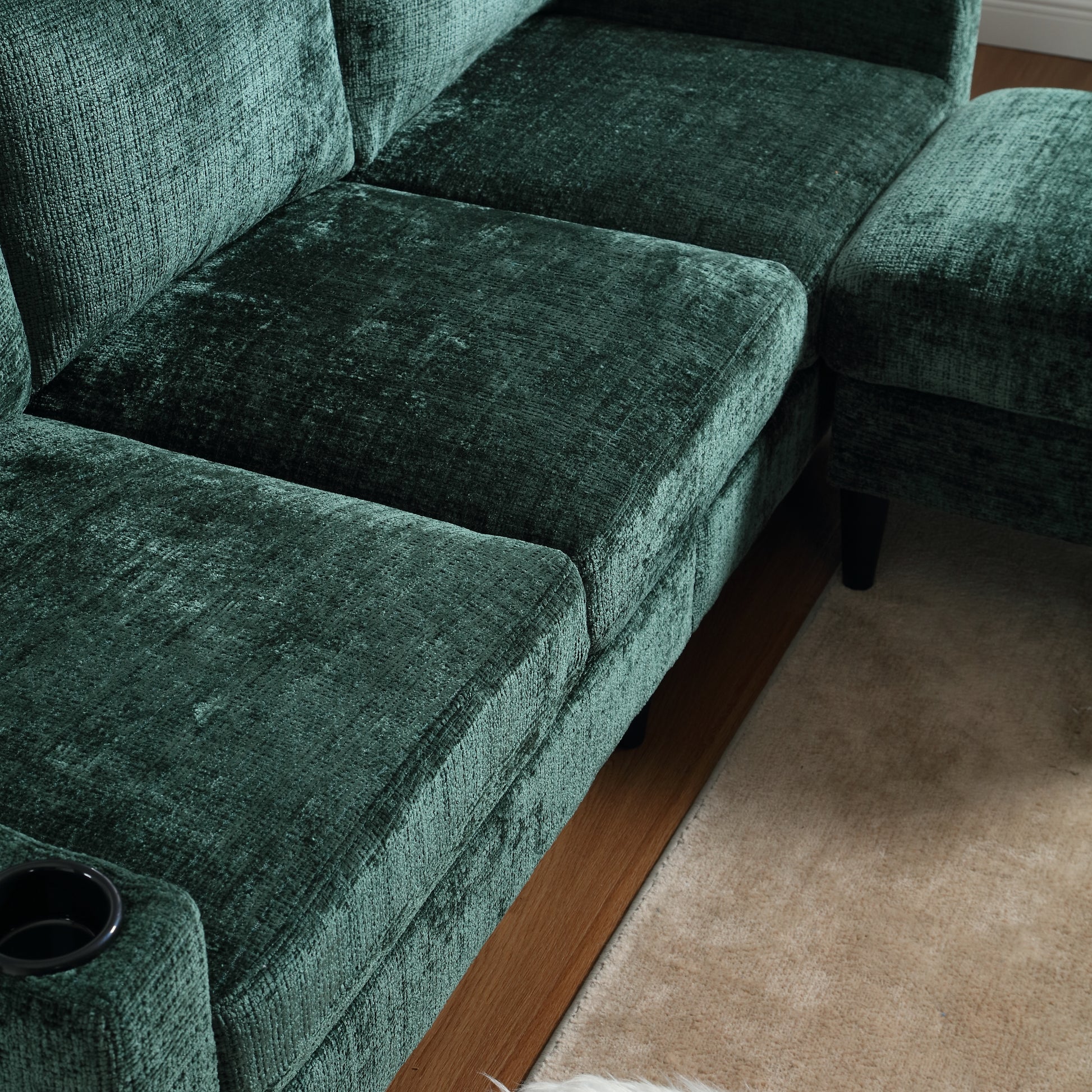 Deep emerald green velvet sectional sofa with a cupholder detail