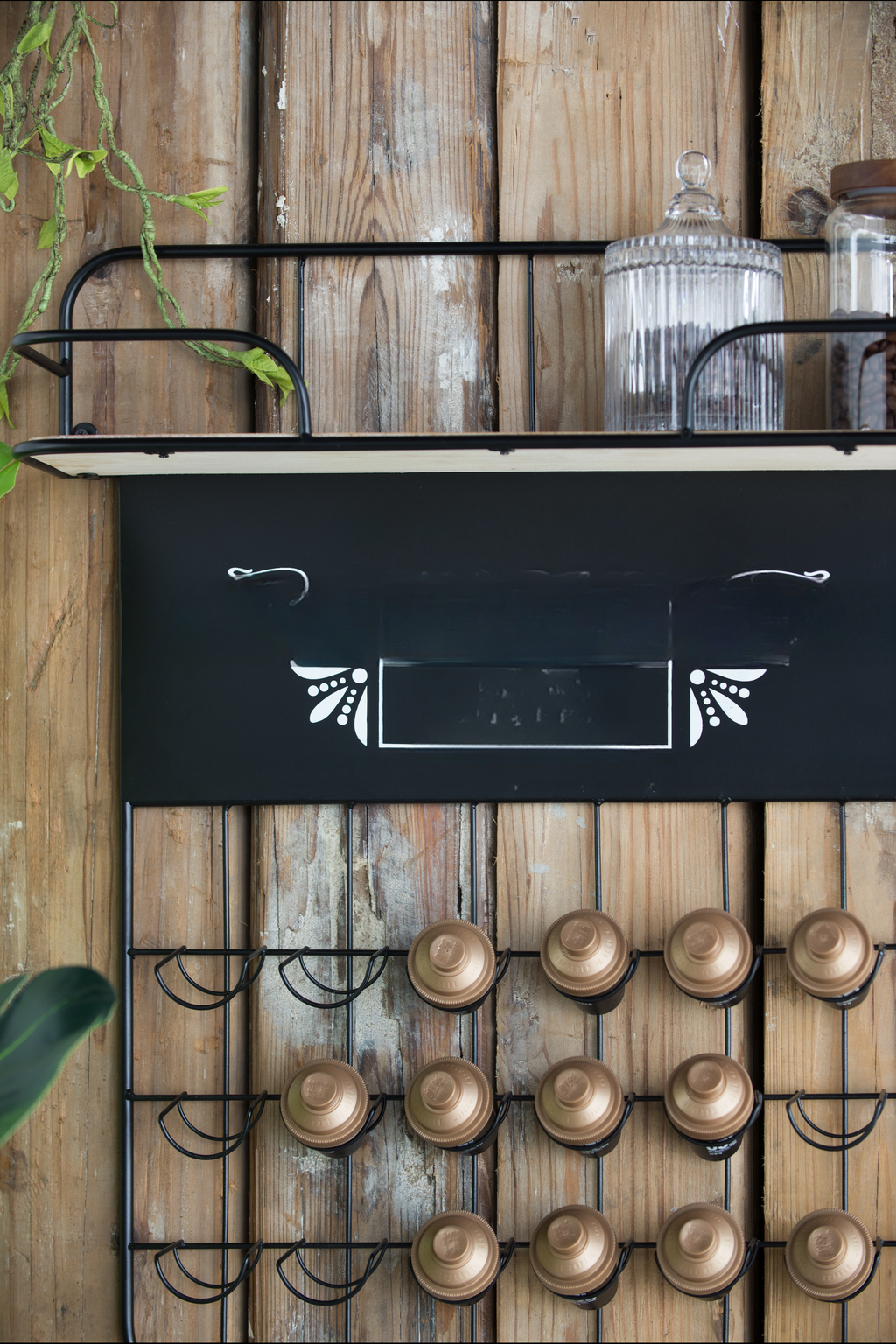 Rustic wallmounted coffee capsule holder with brass pods and decorative blackboard