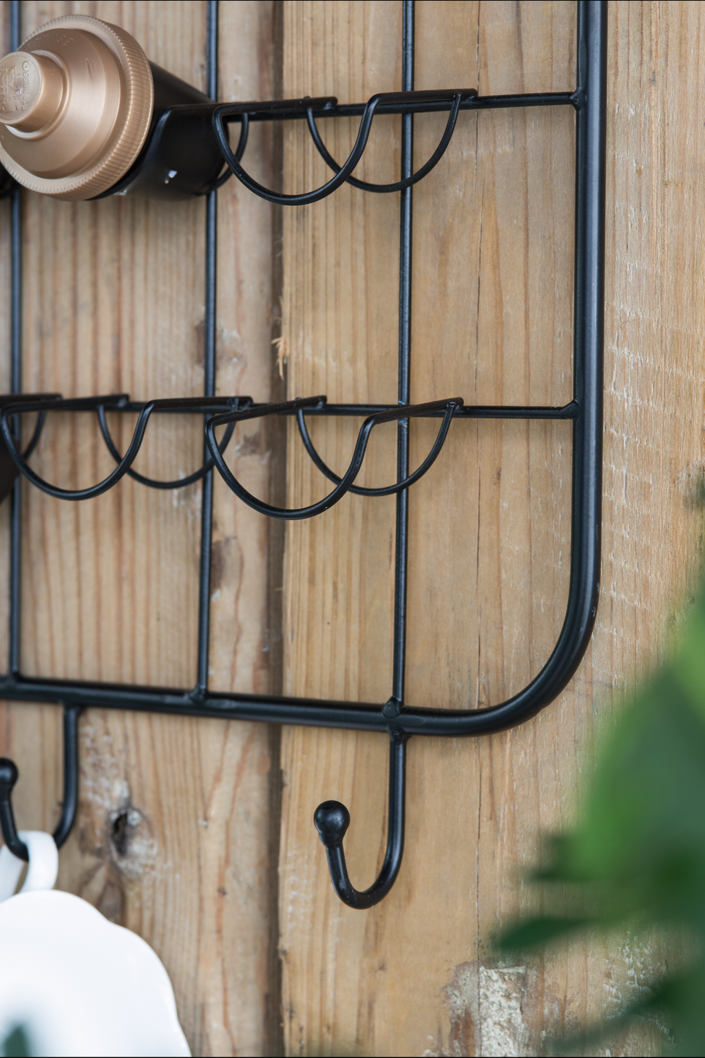 Black metal mug rack with hooks and cup holders on wood background