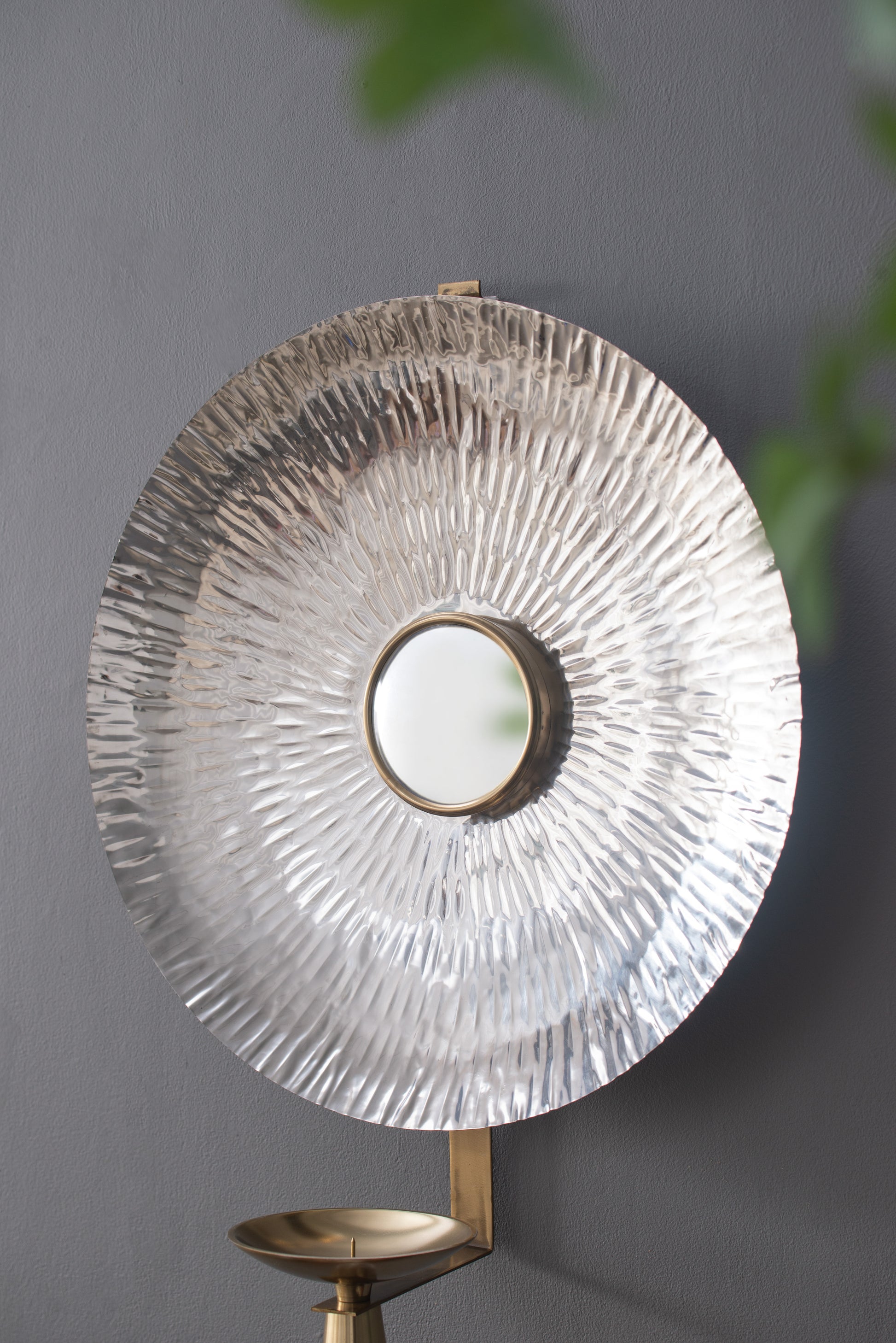 Hammered silver wall sconce with brass accents and a central mirror for elegant home decor