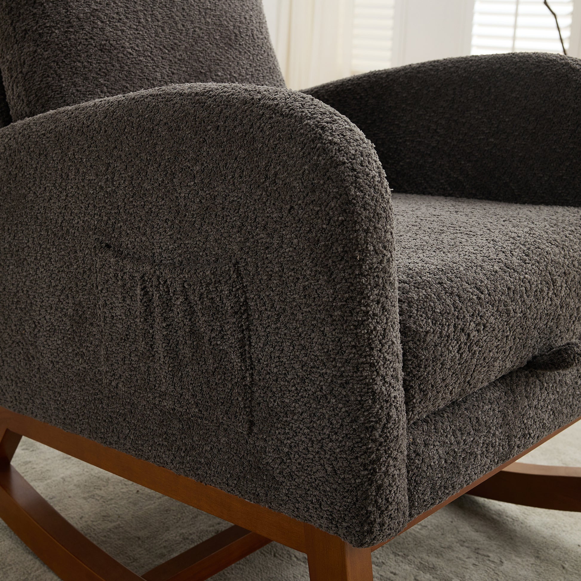 Dark grey boucle fabric armchair with pocket detail and wooden base