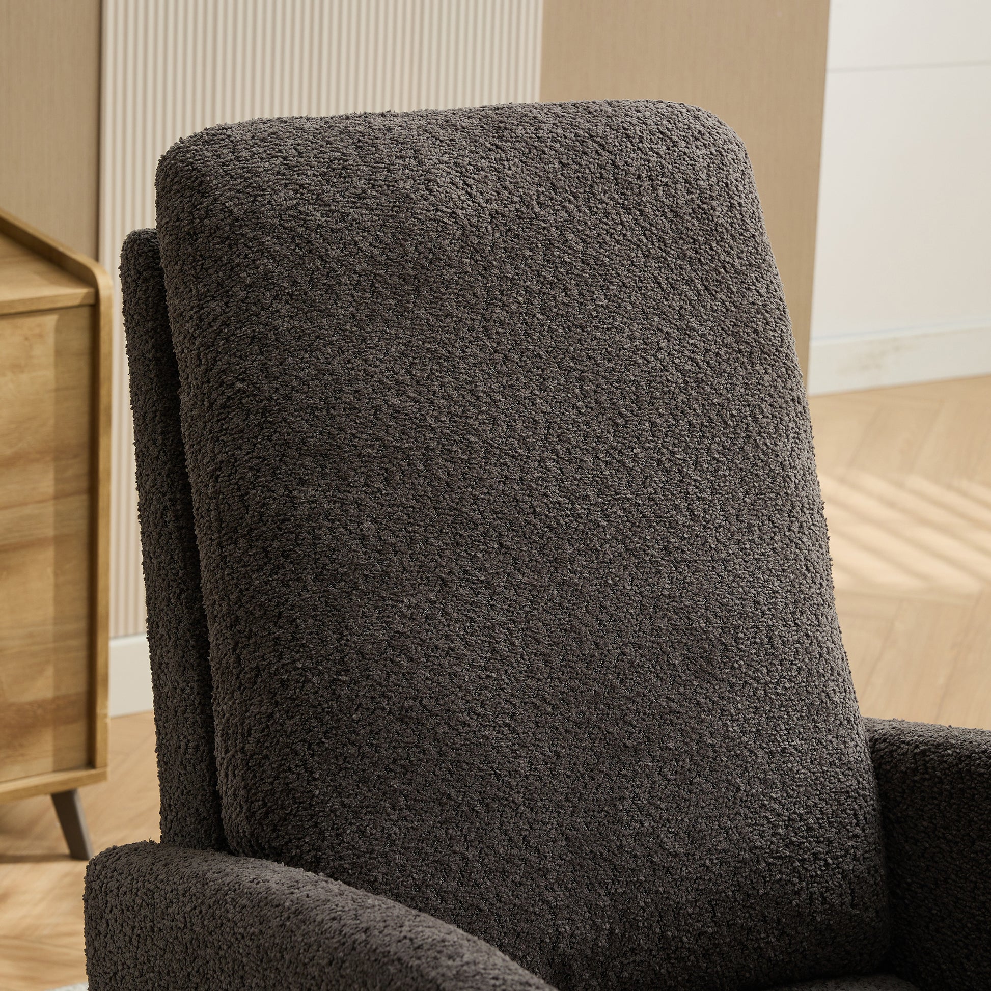 Closeup of a dark grey teddy fabric armchair back and armrest showcasing its plush texture