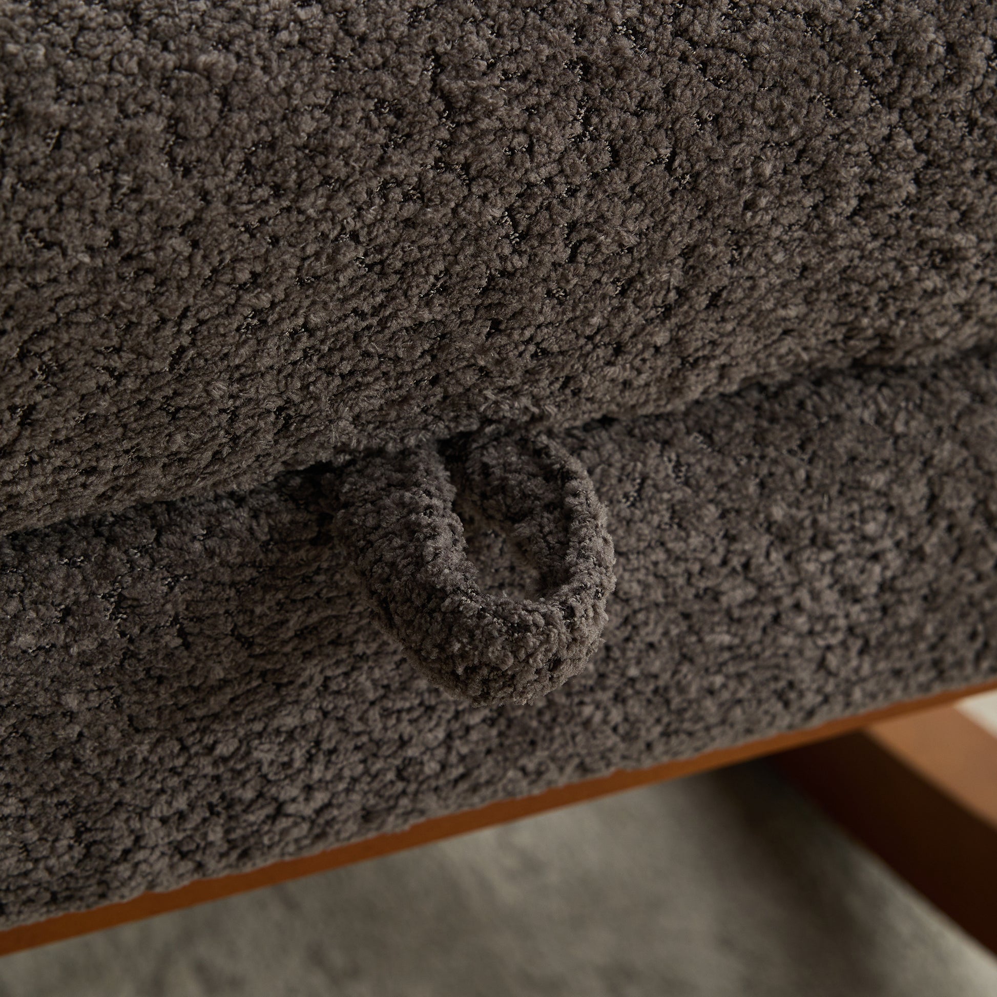 Closeup of textured charcoal grey chenille fabric on a sofa cushion with a loop pull tab