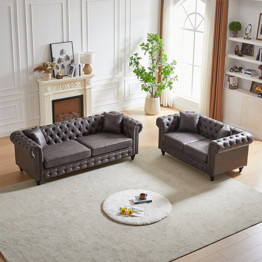 Dark gray tufted leather chesterfield sofa with nailhead trim in a formal living room setting