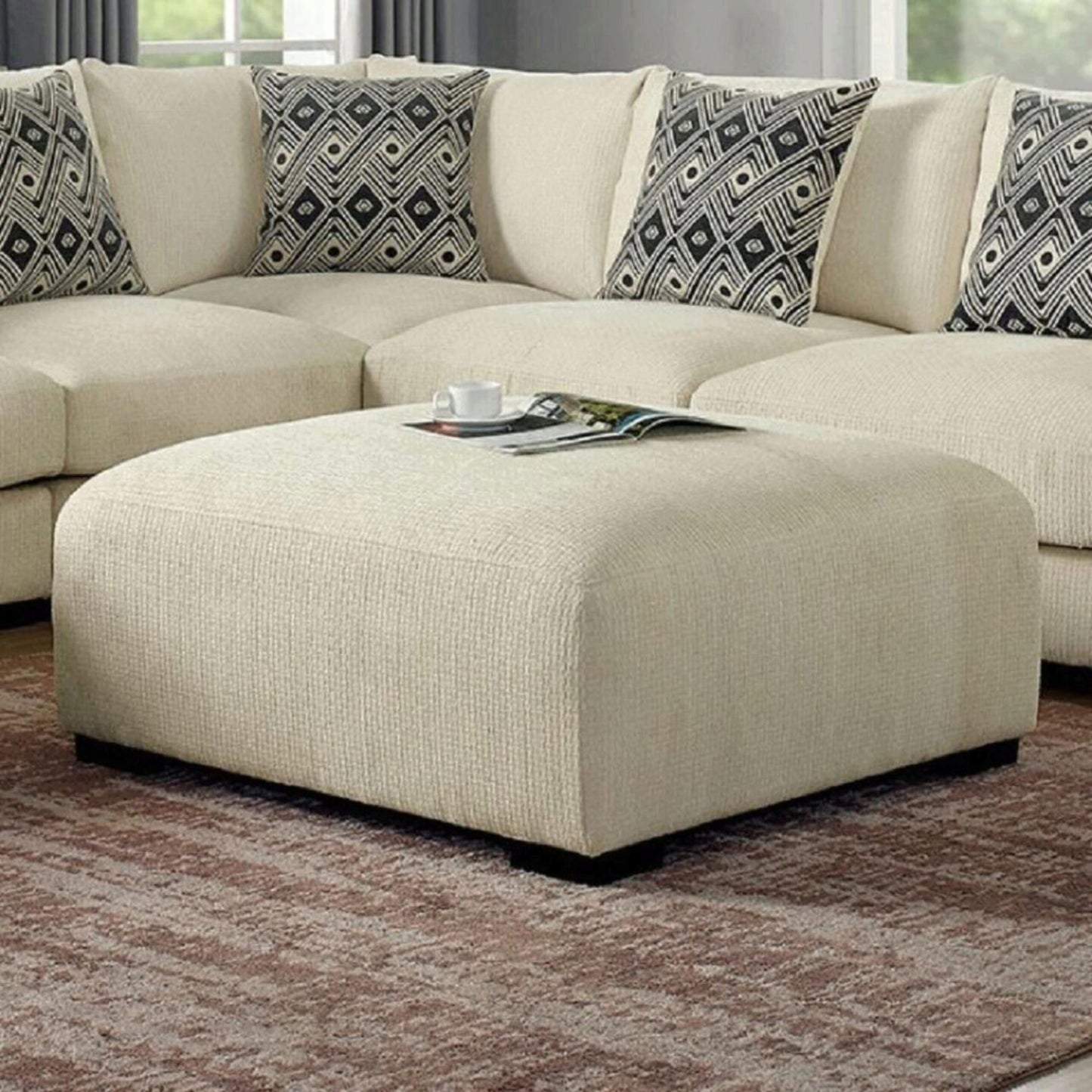Cream textured fabric ottoman with a magazine and cup on top perfect for living room decor