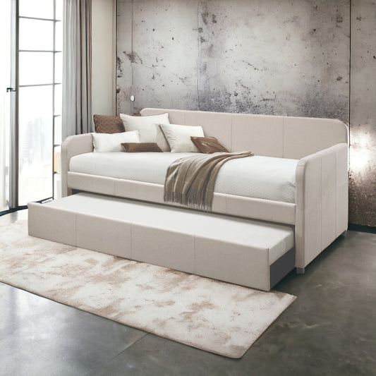 Beige upholstered daybed with a pullout trundle bed and diamondstitched mattress
