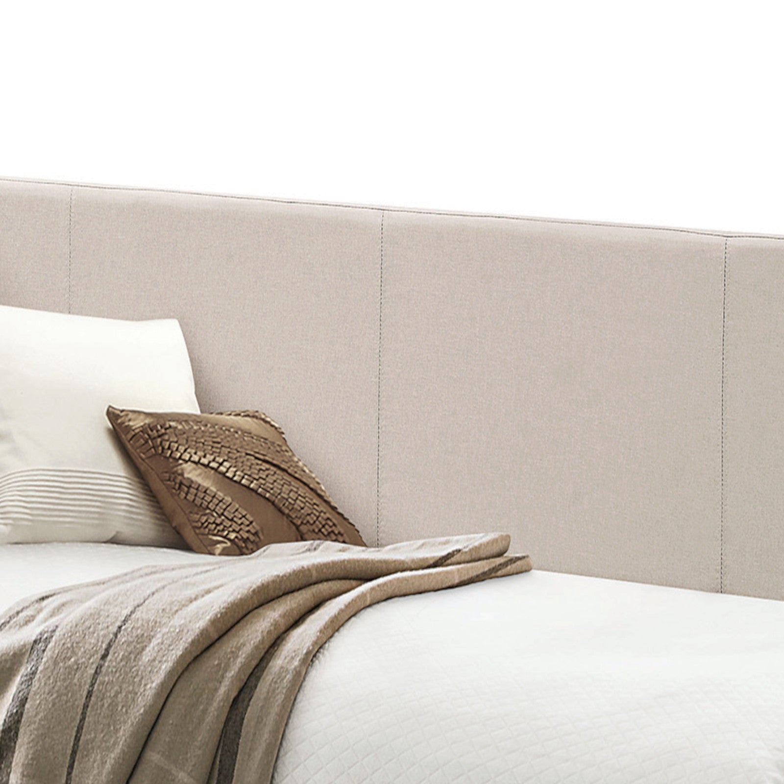 Beige upholstered headboard with neutral pillows and a textured throw blanket