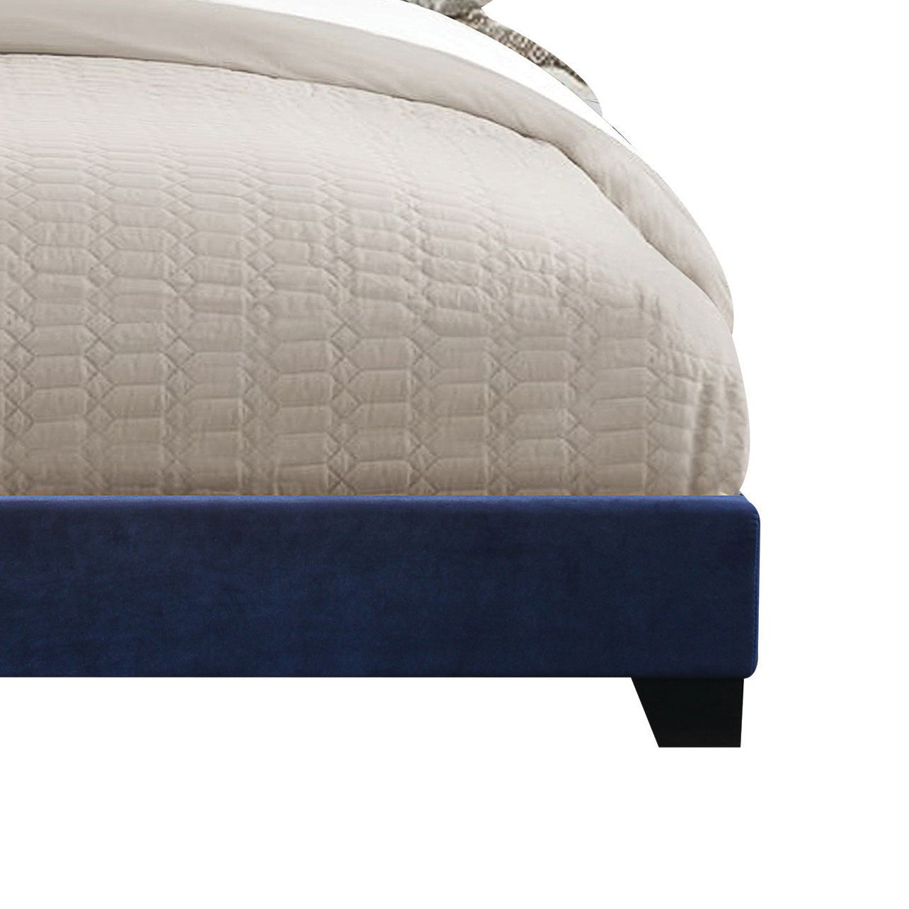 Deep blue velvet upholstered bed frame with a quilted beige comforter closeup